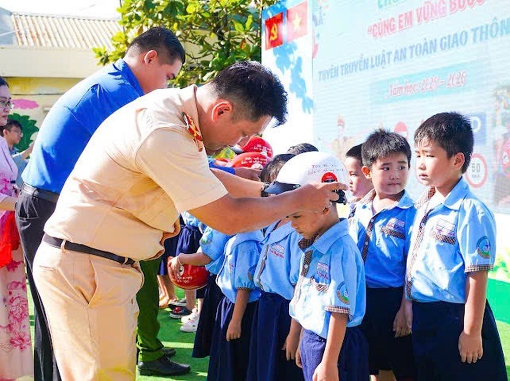 Cán bộ CSGT hướng dẫn học sinh đội mũ bảo hiểm đúng cách