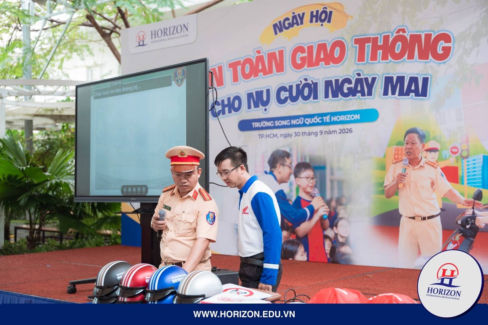 Thiếu tá CSGT và hướng dẫn viên HEAD Việt Thái Quân chuẩn bị mũ bảo hiểm cho học sinh Horizon